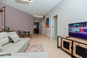 een woonkamer met een witte bank en een flatscreen-tv bij ApartHotel EDA in Durrës