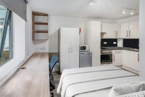 Una pequeña cocina blanca con una cama en una habitación en Modern Studios and Private Bedrooms with Shared Kitchen at Chapter Islington in London en Londres