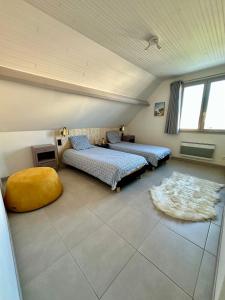 een zolderkamer met 2 bedden en een tapijt bij Anémone in Audresselles