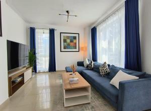 un salon avec un canapé bleu et une télévision dans l'établissement Trinity Holiday Homes - Standpoint Tower Downtown, à Dubaï