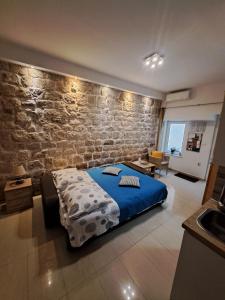 a bedroom with a blue bed and a brick wall at Studio Apartment Legcevic in Kaštela