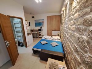 a bedroom with a blue bed and a stone wall at Studio Apartment Legcevic in Kaštela
