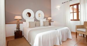 a white bedroom with a large white bed and a chair at Hotel Apartament Sa Tanqueta De Fornalutx - Adults Only in Fornalutx