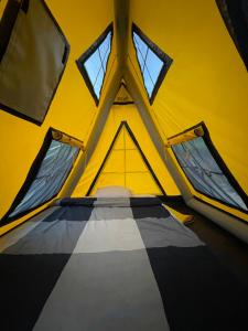 a yellow tent with two windows and a bed in it at Cioclovina Tribe in Cioclovina
