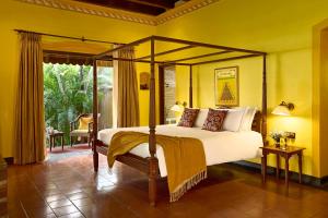 a bedroom with a canopy bed and a patio at Taj Kumarakom Resort and Spa Kerala in Kumarakom