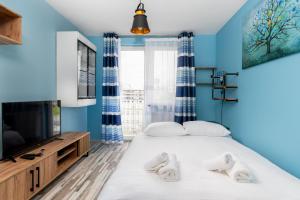 克拉科夫的住宿－Piastów Standard Apartment，一间卧室设有蓝色的墙壁和一张带电视的床。