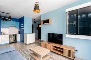 克拉科夫的住宿－Piastów Standard Apartment，客厅设有蓝色的墙壁、一张沙发和一张桌子