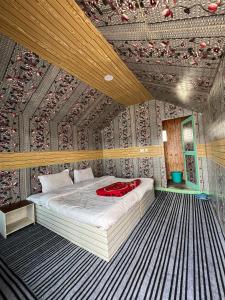 a bedroom with a bed with a red bag on it at Padma Cottage Pangong in Spangmik
