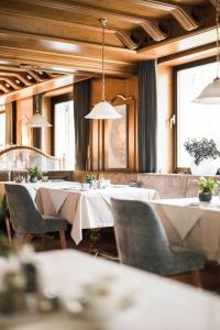 een restaurant met witte tafels, stoelen en ramen bij Hotel Karin in Tirolo
