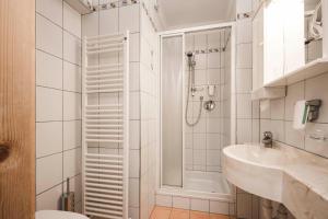 La salle de bains blanche est pourvue d'une douche et d'un lavabo. dans l'établissement Hotel Karin, à Tirolo