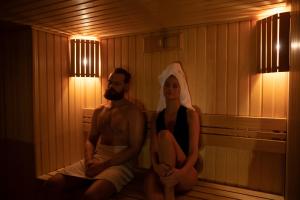un hombre y una mujer sentados en una sauna en Daugirdas Old City Hotel en Kaunas