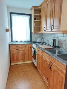 a kitchen with wooden cabinets and a sink and a window at Mandulás nyaraló in Zánka +3 photos