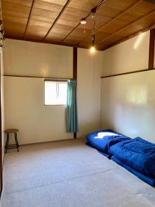a bedroom with a blue bed in a room at 自然の中の古民家ゲストハウスちゃいはな庵 Organic county style classic house Chaihana an in Lake Toya