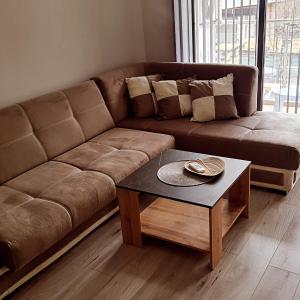 a brown couch in a living room with a table at Апартаменти за Гости ИвАя Казанлък in Kazanlŭk