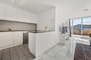 a kitchen with white cabinets and a large window at Spacious Ensuite Room in a City Centre Duplex Apartment-2 in Canberra