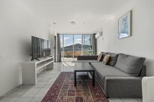 Il comprend un salon doté d'un canapé et d'une télévision à écran plat. dans l'établissement Spacious Ensuite Room in a City Centre Duplex Apartment-2, à Canberra
