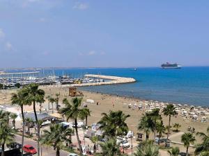 a beach with umbrellas and palm trees and the ocean at Sunorama Beach Garden - Seaview in Larnaca