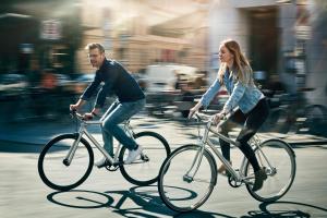 a man and a woman riding bikes down a street at 25hours Hotel Paper Island in Copenhagen