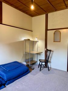 a bedroom with a bed and a chair and a desk at 自然の中の古民家ゲストハウスちゃいはな庵 Organic county style classic house Chaihana an in Lake Toya