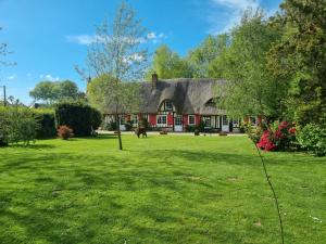 a red and white house with a green yard at La chaumière de jacquotte linge de lits en option in Limpiville
