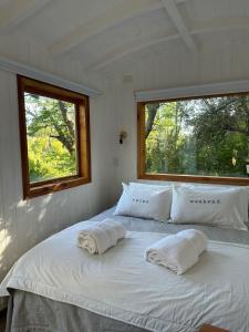- un lit blanc dans une chambre avec 2 fenêtres dans l'établissement Mágica Tiny House con vista a la Montaña, à San Martín de los Andes