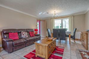 a living room with a leather couch and a table at Starfish Cottage, spacious Norfolk coastal house. - Crabpot Cottages Sheringham in Weybourne