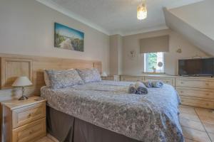 a bedroom with a large bed and a television at Starfish Cottage, spacious Norfolk coastal house. - Crabpot Cottages Sheringham in Weybourne