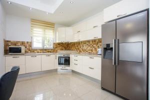 een keuken met witte kasten en een roestvrijstalen koelkast bij Villa Valerija in Srinjine
