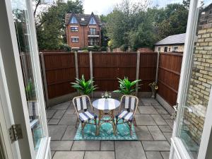 a patio with a table and chairs and a fence at Linden Garden apartment in Bedford