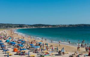 Grupa ludzi na plaży z widokiem na ocean w obiekcie Apartamento Vacacional A Lanzada w mieście Pontevedra