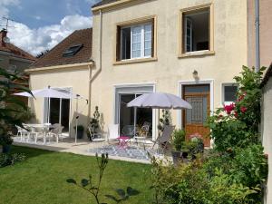 Casa con patio con sillas y sombrilla en Le Claugi, en Damery