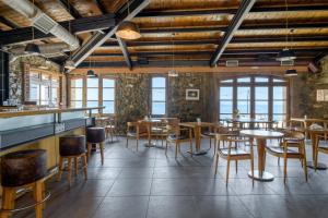 a restaurant with wooden tables and chairs and windows at Kaminos Evia in Limne