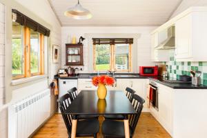 una cocina con una mesa con sillas y un jarrón con flores en Iris Lodge, with cosy Log Burner, 