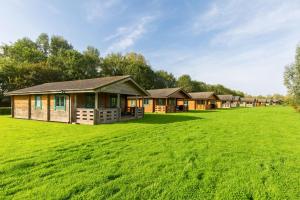 a row of lodges on a large grass field at Iris Lodge, with cosy Log Burner 