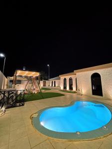 - une grande piscine bleue la nuit dans l'établissement unique chalet, à Unayzah