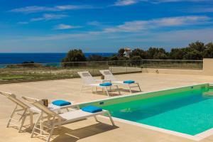 a swimming pool with lounge chairs and the ocean at Villa Lotus - Ionian Villa Collection in Lixouri