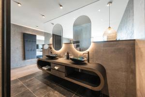 a bathroom with two sinks and two mirrors at DAS GERSTL Alpine Retreat in Malles Venosta