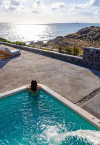 a woman in a swimming pool looking at the ocean at Casa di Mare Luxury Villas in Imerovigli