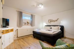 ein Schlafzimmer mit einem Bett, einem Fernseher und einer Couch in der Unterkunft Hüs Wüf im Haus Ornum in Westerland