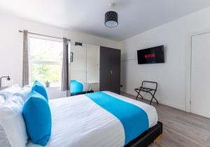 um quarto com uma cama grande e almofadas azuis em Tettenhall Lodge Apartment em Wolverhampton