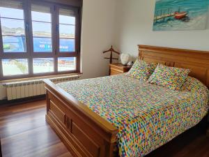 a bedroom with a bed with a colorful comforter and two windows at El Rancho Busto - Luarca in Busto