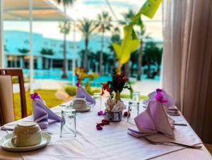 uma mesa com uma toalha de mesa branca e guardanapos roxos em Hammamet Serail em Hammamet