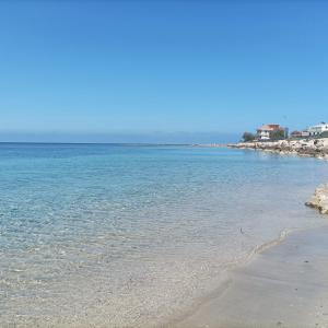 a beach with blue water and rocks on the shore w obiekcie IL MELOGRANO RESIDENCE MARZAMEMI w mieście Marzamemi