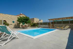 a swimming pool in a yard with chairs and a house at Orelia Cretan Deluxe Apartments in Kamilari