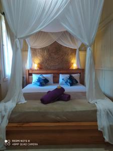 Schlafzimmer mit einem Bett mit weißen Vorhängen in der Unterkunft ASHVATTHA VILLA Canggu in Canggu