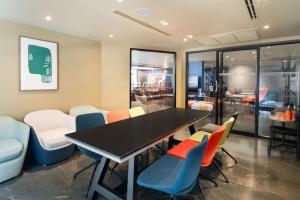 a dining room with a black table and colorful chairs at Lumen Bangkok Udomsuk Station in Bangkok