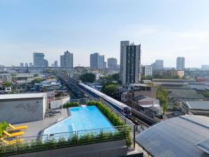 Blick auf eine Stadt mit Pool und Zug in der Unterkunft Lumen Bangkok Udomsuk Station in Bangkok