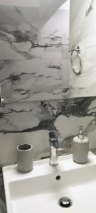 baño con lavabo blanco con una pintura en la pared en Sevilia Rooms, en Qeparo