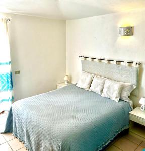 1 dormitorio con cama azul y almohadas blancas en casa a pochi minuti dalla spiaggia di vignola, en Vignola Mare