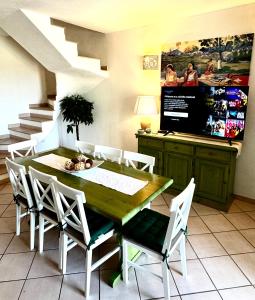 uma sala de jantar com uma mesa de madeira e cadeiras brancas em casa a pochi minuti dalla spiaggia di vignola em Vignola Mare